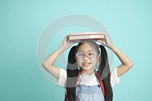 Portrait of happy lazy little girl covering head with book and smiling to camera.