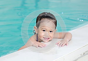 Portrait of happy little Asian child girl learning to swim in pool