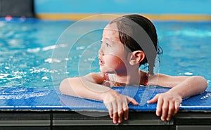 Portrait of happy little Asian child girl learning to swim in pool. Close-up short