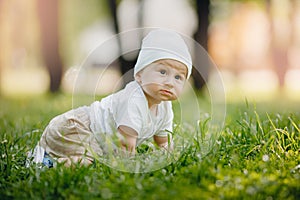 Portrait of happy little baby boy crawling in green grass on summer health outdoor sports for children
