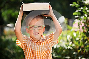 Portrait Happy little boy holding a big book on his first day to school or nursery. Outdoors, Back to school concept