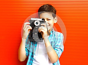 Portrait happy little boy teenager with retro camera on red