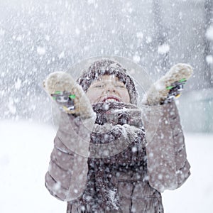 Portrait of a happy little girl on the background of a winter pa