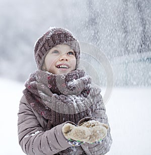 Portrait of a happy little girl on the background of a winter pa