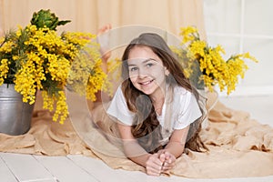 Portrait happy little girl with bouquet spring mimosa flowers. Branches mimosa yellow in vase. Mother's day.