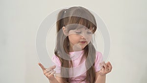 A portrait happy little girl with brown hair smiles and counting with her fingers isolated on white background. Child