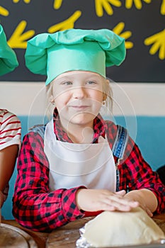 Portrait of a happy little girl in a chef`s cap and apron