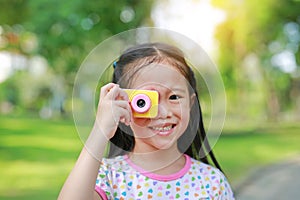 Portrait of happy little girl with digital camera toy in the garden outdoor