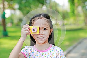 Portrait of happy little girl with digital camera toy in the garden outdoor