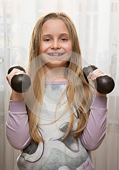 Portrait of happy little girl with dumbbells