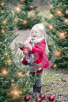 Portrait of happy little girl hanging baubles on tree at farm