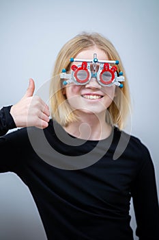 portrait happy little girl patient ophthalmology clinic, vision test in progress cheerful child trying on trial frames