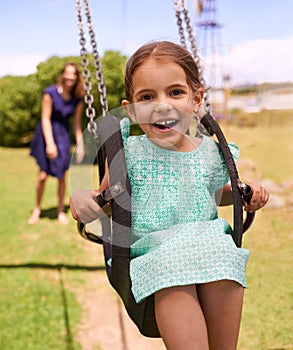 Portrait, happy little girl ride on swing and in the park watching sunset. Cute toddler, having fun woman swinging her