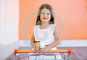 Portrait happy little girl in shopping cart with tasty ice cream