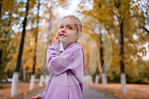 Portrait of happy little girl in yellow autumn park. Fall season.