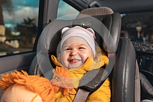 Portrait of a happy little kid sitting in a child seat in the back seat of a car. The concept of safe trip and child