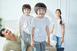 Portrait of happy little latin boy smiling at camera while having fun his father and siblings at home