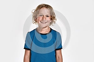 Portrait of happy little sportive boy child in sportswear smiling at camera while posing, standing isolated over white