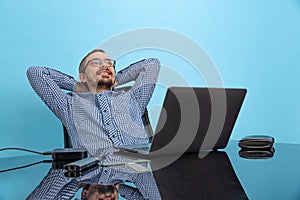 Portrait of happy looking man, computer support specialist, programmer sitting in front of laptop isolated over blue