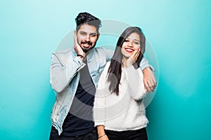 Portrait of happy lovely indian couple smiling and posing on camera while pleasend signs together over green background