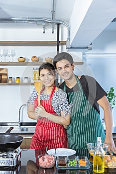 Portrait of happy lovely young Asian couple in love with casual clothes in modern kitchen, is smiling, looking at camera and