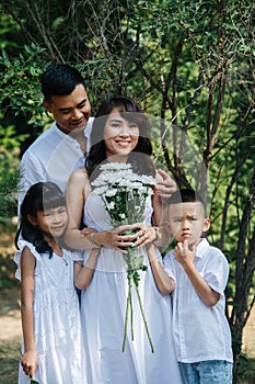 Portrait of a happy loving asian family in white clothes in a park