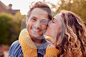 Portrait Of Happy Loving Couple With Woman Giving Man Kiss On The Cheek