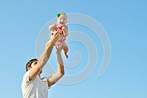 Portrait of happy loving father and her baby outdoors. Daddy and child against summer blue sky.