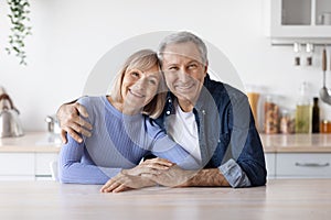 Portrait of happy loving senior couple posing together at kitchen