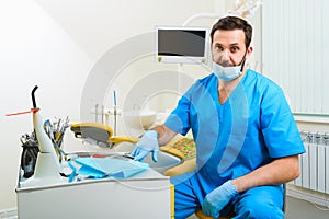 Portrait of happy male dentist wearing lab coat while sitting in clinic