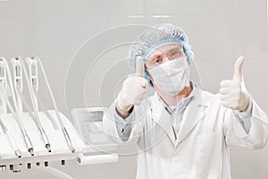 Portrait of happy male dentist wearing lab coat while sitting in clinic