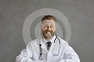 Portrait of happy male doctor looking away, thinking about something, smiling and laughing