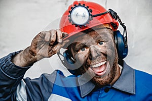 Portrait happy male miner after working in coal mine, dirty face in helmet