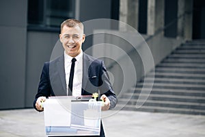 Portrait happy male office worker with box of personal stuff. Unemployment concept. Left without money. Businessman lost