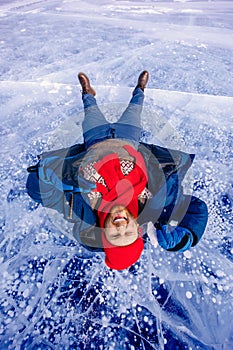 Portrait happy male tourist in red hat with shard of transparent ice in winter on Lake Baikal sunset