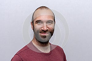 Portrait of a happy man 30-35 years old, bald and with a beard on a light background.