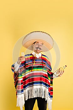 Portrait of happy man in bright garment, poncho isolated over yellow background