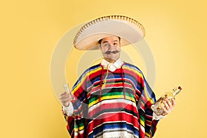 Portrait of happy man in bright garment, poncho isolated over yellow background