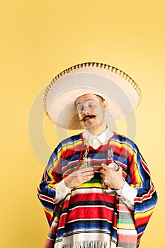 Portrait of happy man in bright garment, poncho isolated over yellow background