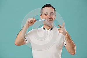 Portrait of Happy Man Brushing Teeth on Blue