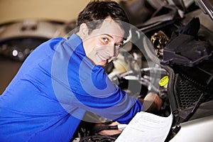 Portrait, happy man and mechanic with document on engine of car, repair or maintenance. Smile, face and technician with