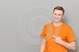 Portrait of happy man pointing with finger at empty place and smiling