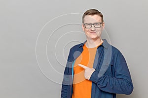 Portrait of happy man pointing with finger at empty place and smiling