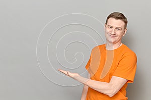 Portrait of happy man pointing with hand at empty place and smiling