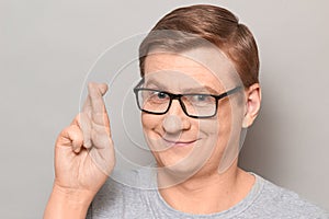 Portrait of happy man raising crossed fingers and hoping for victory