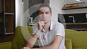 Portrait of happy man is resting while sitting on couch at home. A young male enjoys the lifestyle looking at the camera