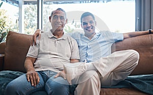 Portrait of happy man with senior father on sofa, happiness and quality time together in living room of home in Mexico