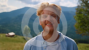 Portrait happy man smiling on green meadow. Red hair guy relaxing on vacation.