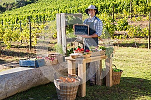 Portrait of happy man standing with slate at vegetable stall