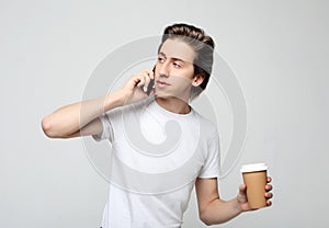 Portrait of happy man talking on phone and drinking coffee